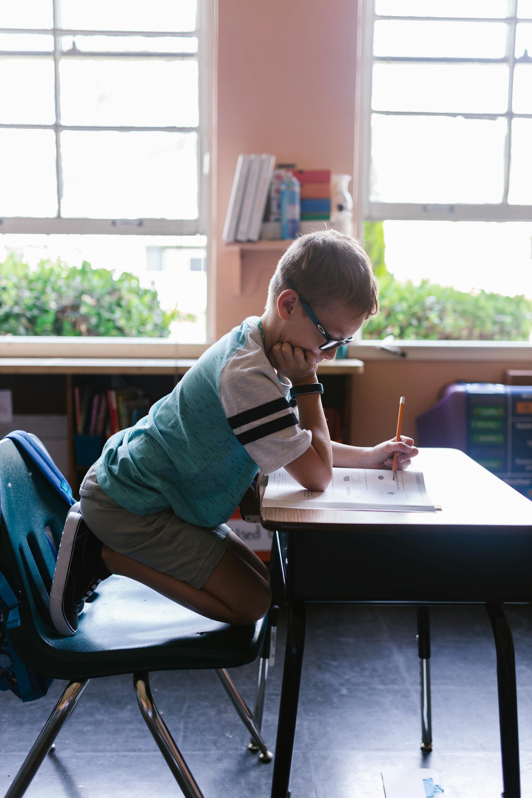 A young boy diligently doing homework at a classroom desk, surrounded by a vibrant learning environment.